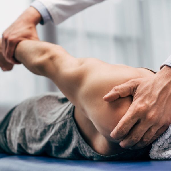 selective focus of chiropractor stretching arm of patient in hospital
